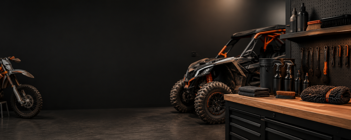 A black and orange Polaris side-by-side UTV is parked in a dark workshop next to a wooden workbench with tools, with another vehicle partially visible on the far left.